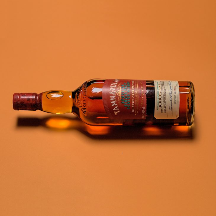 A bottle of Tamnavulin whisky on amber background.