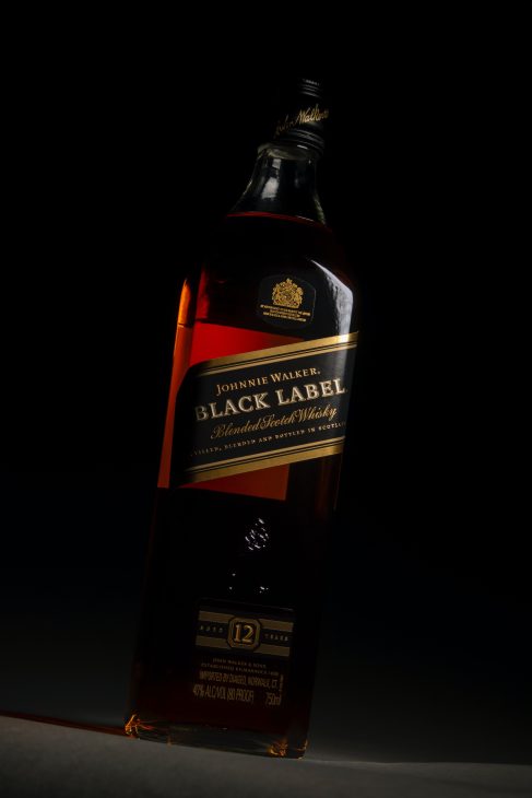 Bottle of Johnnie Walker Black Label Scotch Whiskey on a black background dark lit.