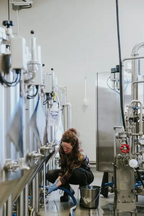 A woman adjusts the valves of the hot water machine as she prepares for the next step in the brewing process.